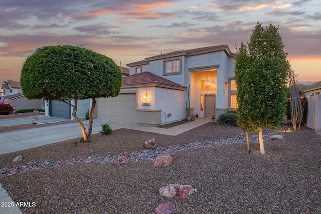 view of front of home featuring stucco siding, driveway, a garage, and a tiled roof