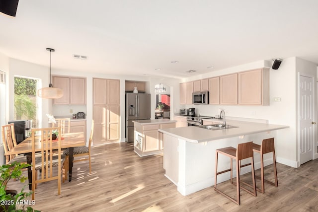 kitchen with light countertops, a kitchen island, light wood finished floors, stainless steel appliances, and visible vents