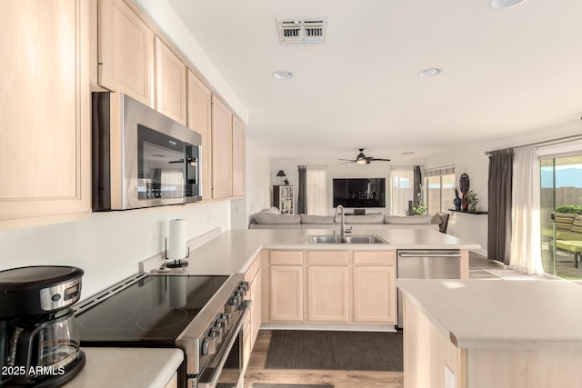 kitchen with visible vents, a peninsula, stainless steel appliances, a sink, and open floor plan