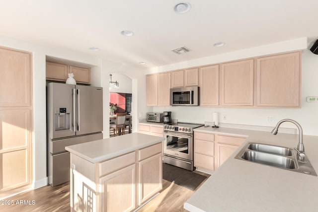 kitchen featuring light brown cabinets, light countertops, a sink, and stainless steel appliances