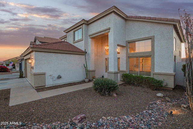 view of front of property featuring stucco siding, a garage, and a tiled roof