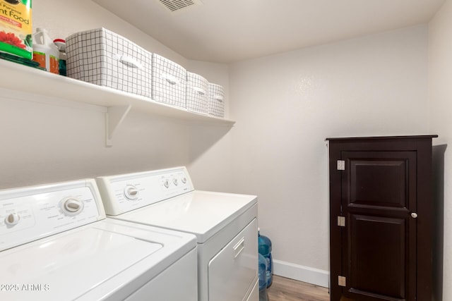 washroom featuring washing machine and clothes dryer, baseboards, laundry area, and light wood-type flooring