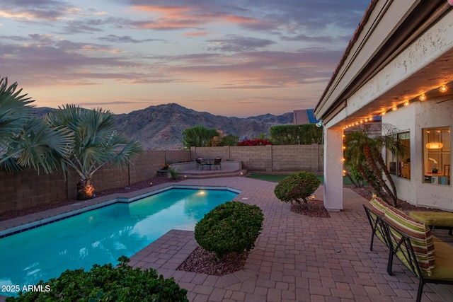 view of swimming pool featuring a patio, a mountain view, a fenced backyard, and a fenced in pool