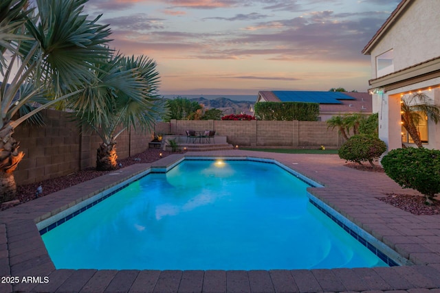 pool at dusk with a fenced backyard and a fenced in pool