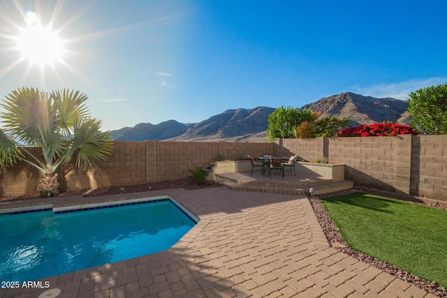view of swimming pool featuring a fenced backyard, a fenced in pool, a mountain view, and a patio area