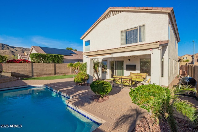 back of property with a patio area, a fenced in pool, stucco siding, a fenced backyard, and a tiled roof