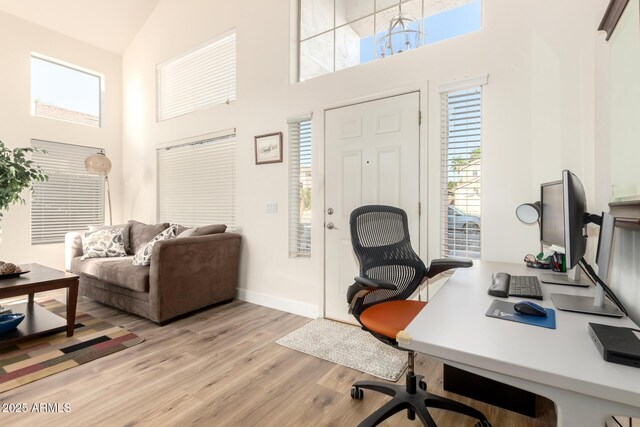 office area with baseboards, high vaulted ceiling, and light wood-style floors