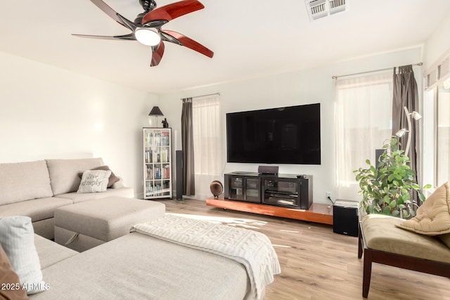 living area featuring visible vents, a ceiling fan, and wood finished floors