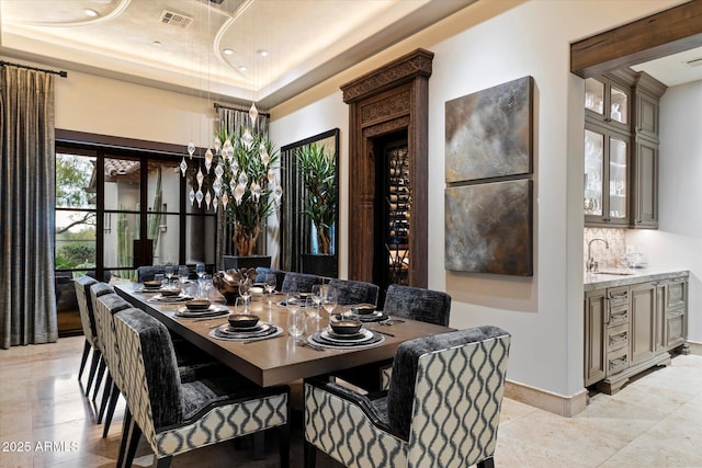 dining space with wet bar and a tray ceiling