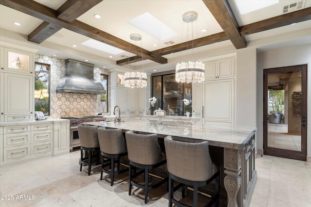 kitchen featuring premium range hood, decorative light fixtures, high end stove, light stone counters, and a spacious island