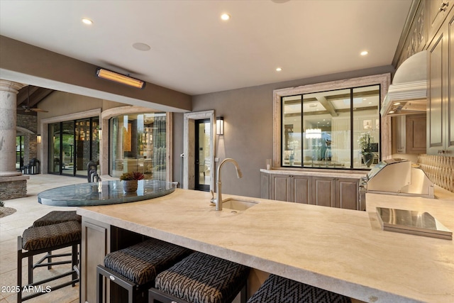 kitchen with a kitchen bar, sink, and custom exhaust hood