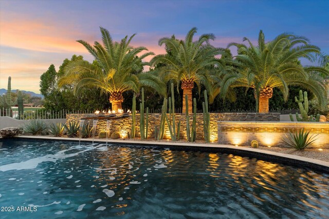 pool at dusk featuring pool water feature