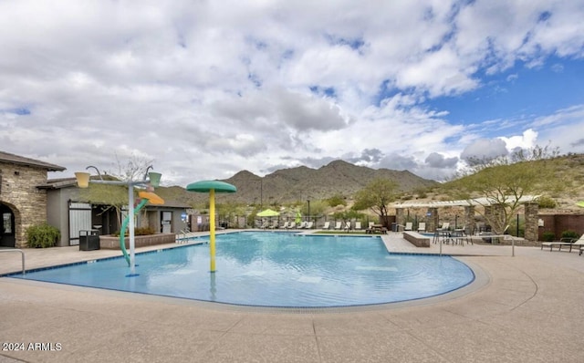 view of pool with a mountain view, pool water feature, and a patio area