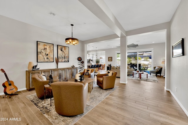 living room featuring light wood-type flooring and ceiling fan with notable chandelier