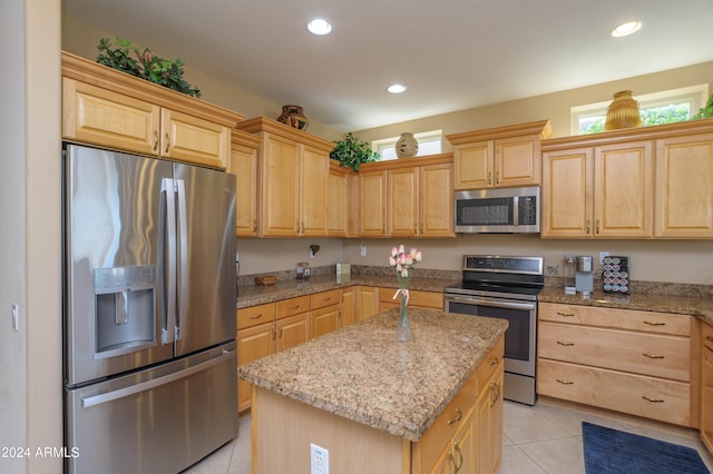 kitchen with light stone counters, light tile patterned floors, appliances with stainless steel finishes, and a kitchen island