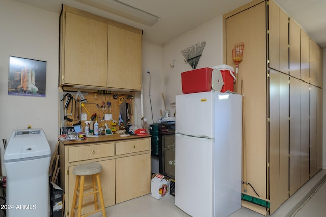 kitchen featuring light brown cabinetry, white fridge, and tasteful backsplash