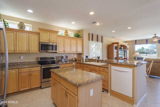 kitchen with ceiling fan, sink, kitchen peninsula, a kitchen island, and appliances with stainless steel finishes