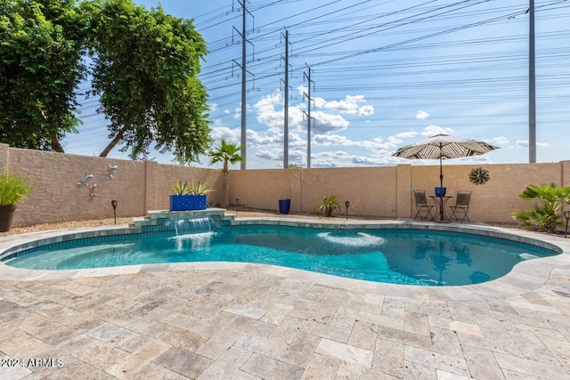 view of swimming pool with pool water feature and a hot tub