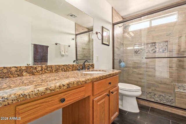 bathroom with an enclosed shower, vanity, toilet, and tile patterned flooring