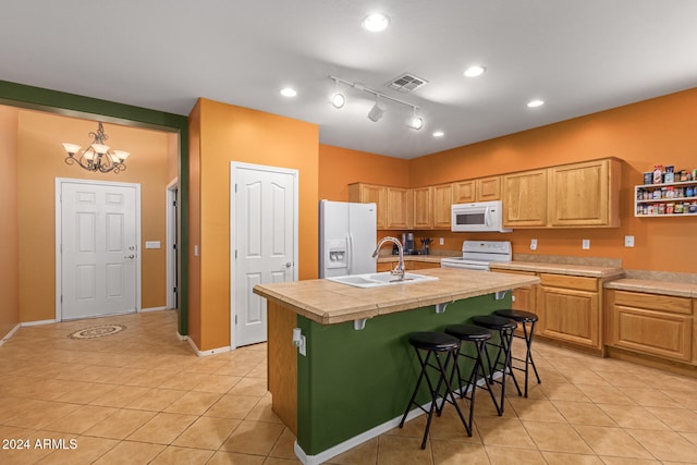 kitchen featuring a breakfast bar area, a kitchen island with sink, a notable chandelier, sink, and white appliances