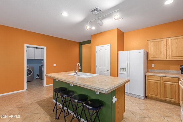 kitchen featuring washer / dryer, an island with sink, sink, a kitchen bar, and white appliances