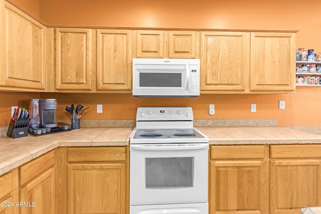 kitchen with tile countertops, light brown cabinets, and white appliances