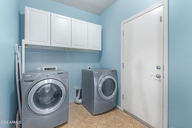 laundry room featuring cabinets, light tile patterned flooring, and washer and clothes dryer