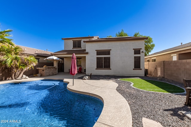 back of property featuring a patio area, a fenced in pool, and an outdoor kitchen