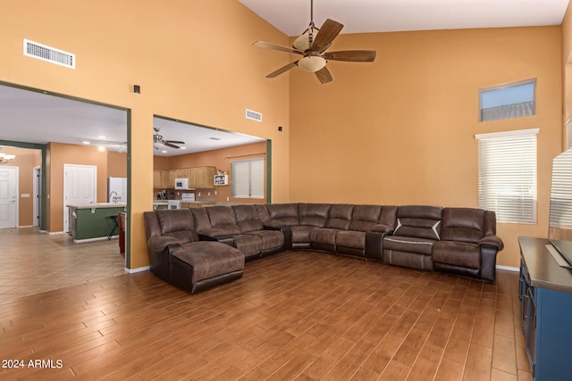 living room with ceiling fan, high vaulted ceiling, sink, and light wood-type flooring