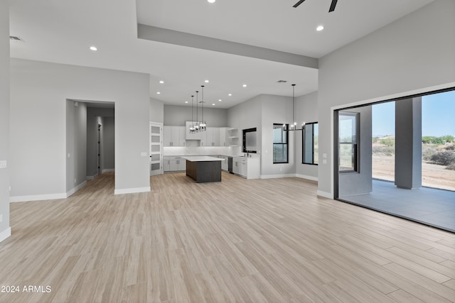 unfurnished living room with light hardwood / wood-style flooring and ceiling fan with notable chandelier