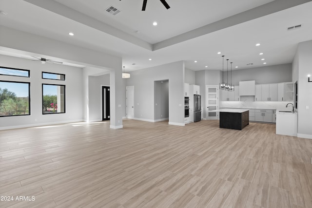 unfurnished living room with ceiling fan, sink, and light wood-type flooring