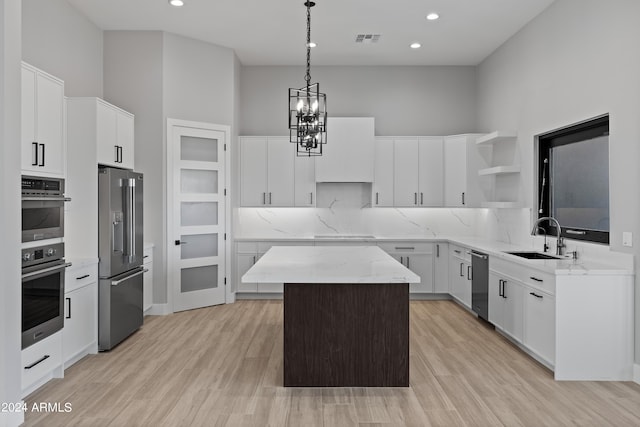 kitchen with appliances with stainless steel finishes, a center island, hanging light fixtures, and a towering ceiling