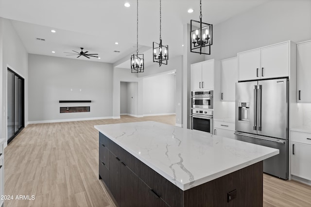 kitchen featuring a kitchen island, light hardwood / wood-style flooring, stainless steel appliances, decorative light fixtures, and white cabinets