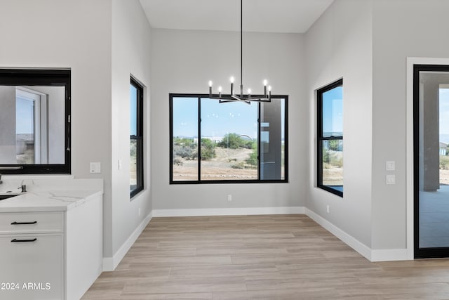 unfurnished dining area featuring light hardwood / wood-style flooring and a chandelier