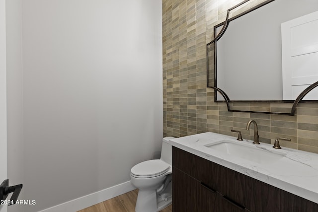 bathroom with toilet, tasteful backsplash, vanity, and wood-type flooring