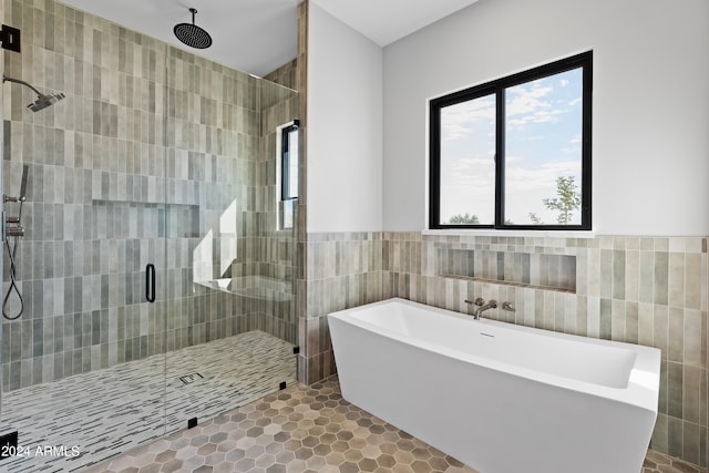 bathroom with tile patterned floors, tile walls, and separate shower and tub