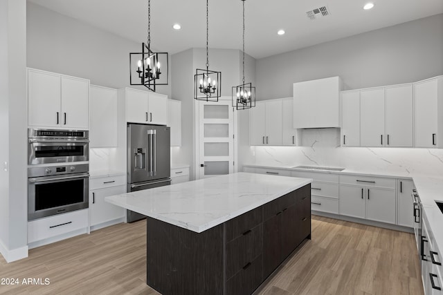 kitchen with a kitchen island, decorative backsplash, light hardwood / wood-style flooring, stainless steel appliances, and white cabinets