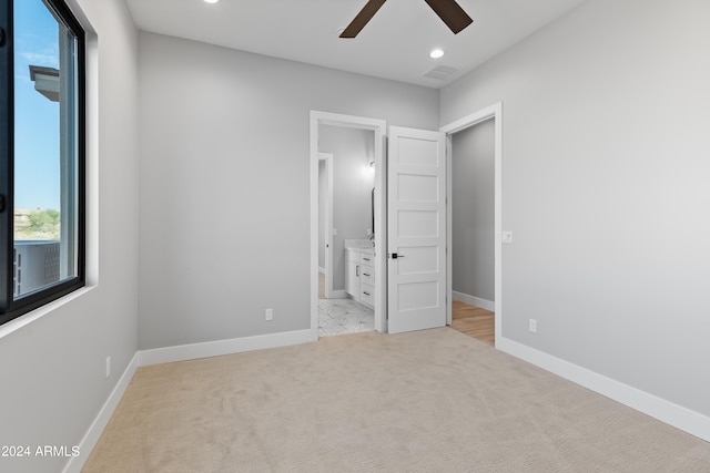 unfurnished bedroom with ceiling fan, light colored carpet, and ensuite bath