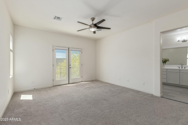 carpeted spare room featuring a sink, baseboards, a ceiling fan, and visible vents