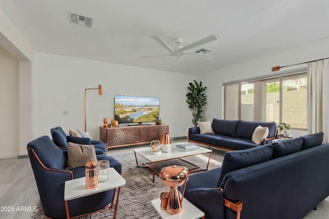 living room featuring a ceiling fan, visible vents, and light wood-style flooring