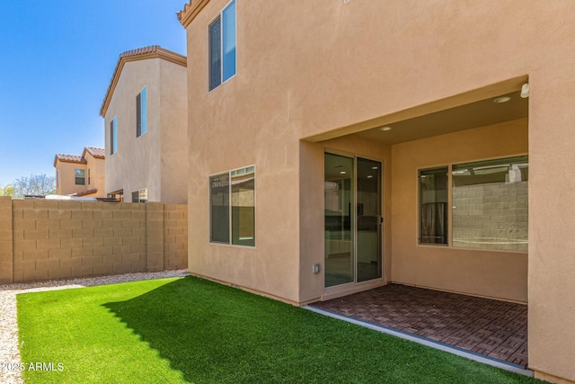 back of house featuring stucco siding, a lawn, fence, and a patio area