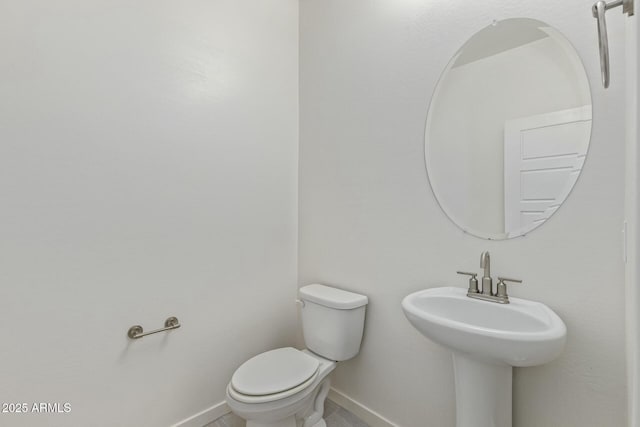 bathroom featuring baseboards, a sink, and toilet