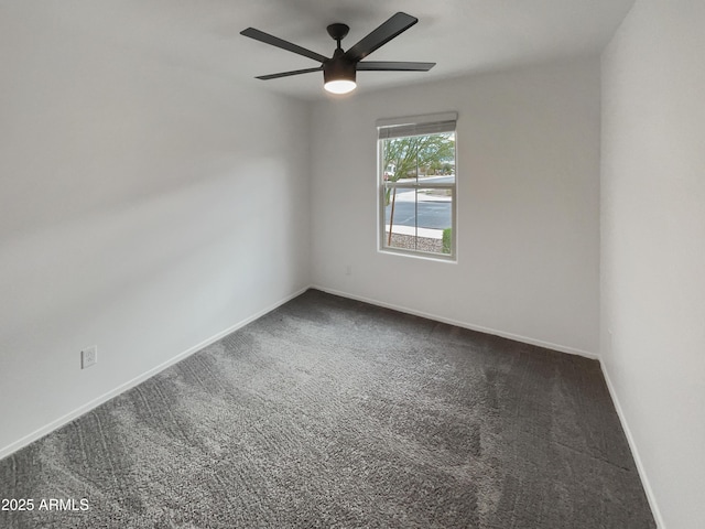 unfurnished room with a ceiling fan, dark carpet, and baseboards