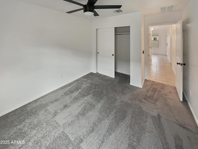 unfurnished bedroom featuring carpet floors, visible vents, a closet, and tile patterned floors