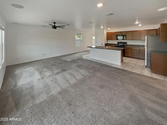 kitchen featuring light carpet, a sink, visible vents, black appliances, and dark countertops