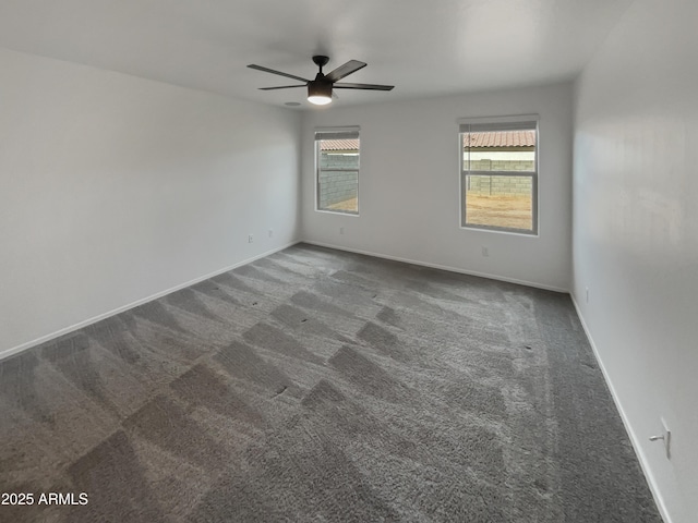 empty room with dark carpet, a ceiling fan, and baseboards