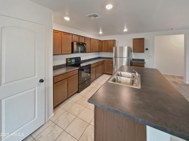 kitchen featuring a kitchen island with sink, a sink, visible vents, black appliances, and dark countertops