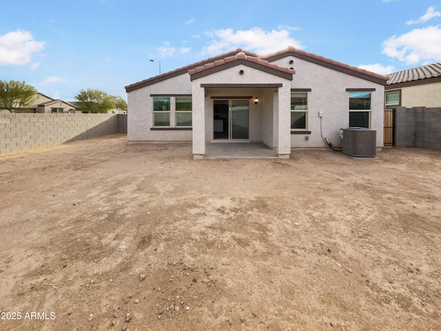 rear view of property with stucco siding, a fenced backyard, cooling unit, and a tiled roof