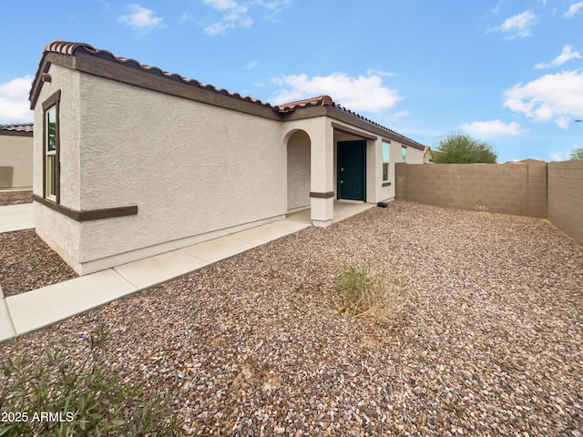 view of front facade with a tile roof, a fenced backyard, and stucco siding