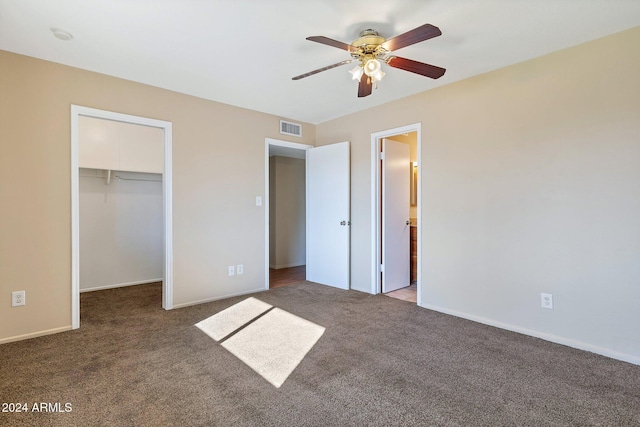 unfurnished bedroom featuring carpet flooring, a spacious closet, a closet, and ceiling fan